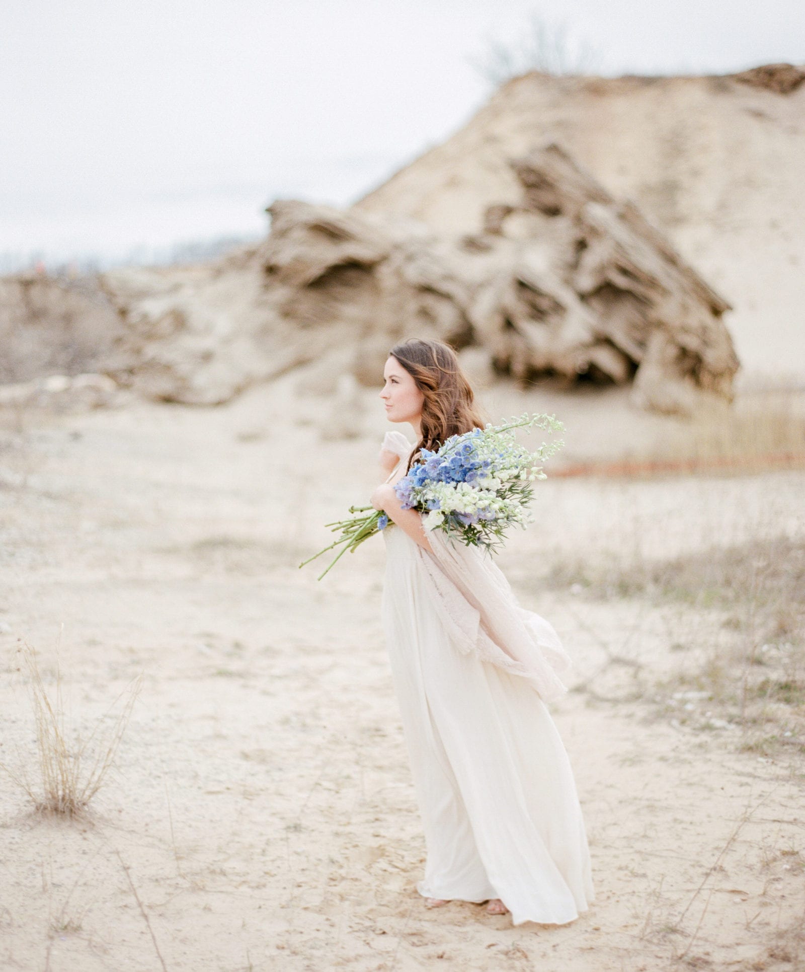 bride with blue and white flowers in sand dunes